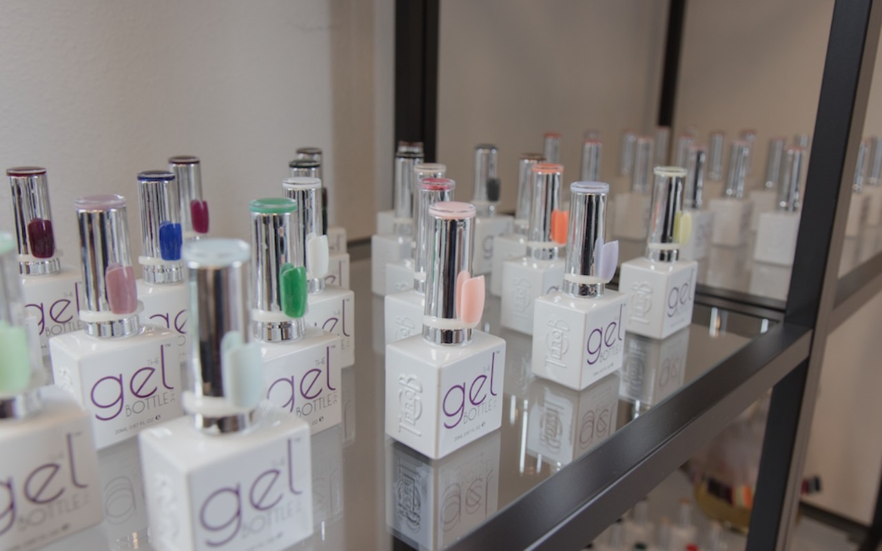 Rijen flesjes gellak van The Gel Bottle op glazen planken
